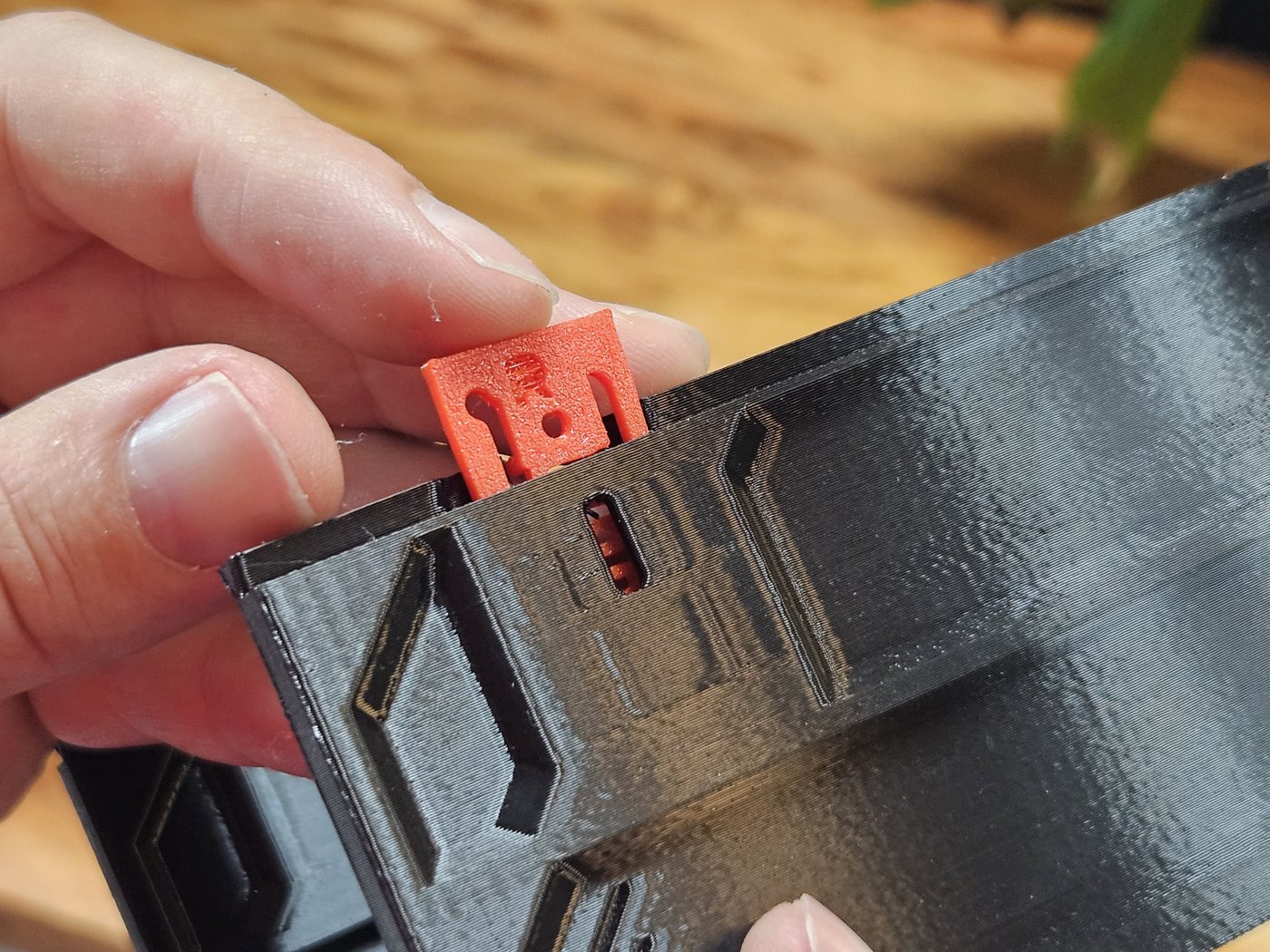 Fingers pressing a red Bi-Directional QuickLock down into the slot at the top of a black case wall